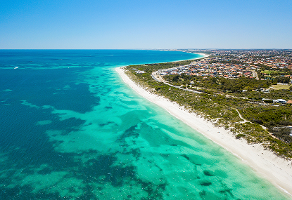 Aerial view of a blue beach with the ocean in the background, showcasing a serene and inviting coastal scene
