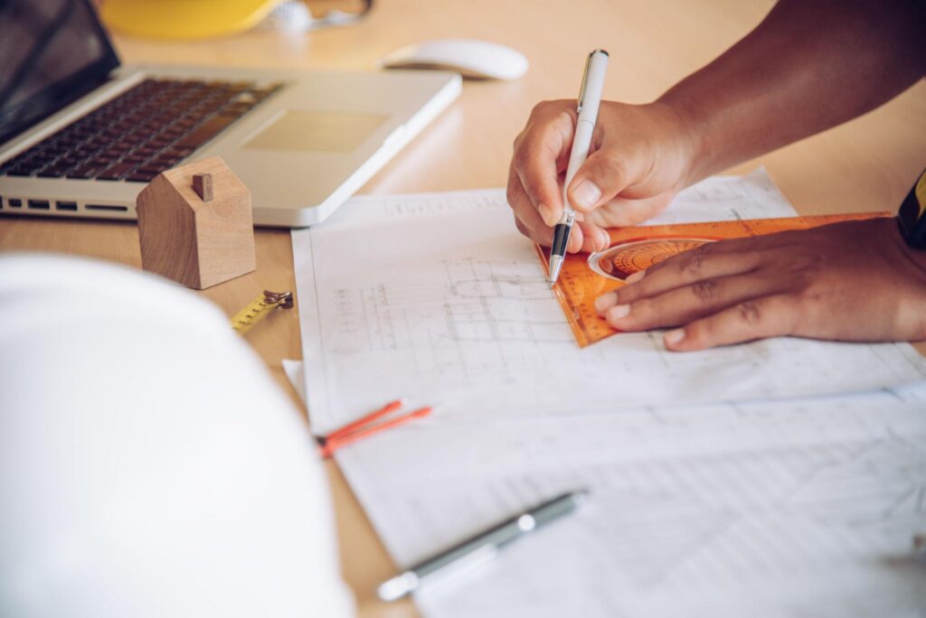 A person working on a project using a laptop and a pencil at TAP Hydraulic Consulting office